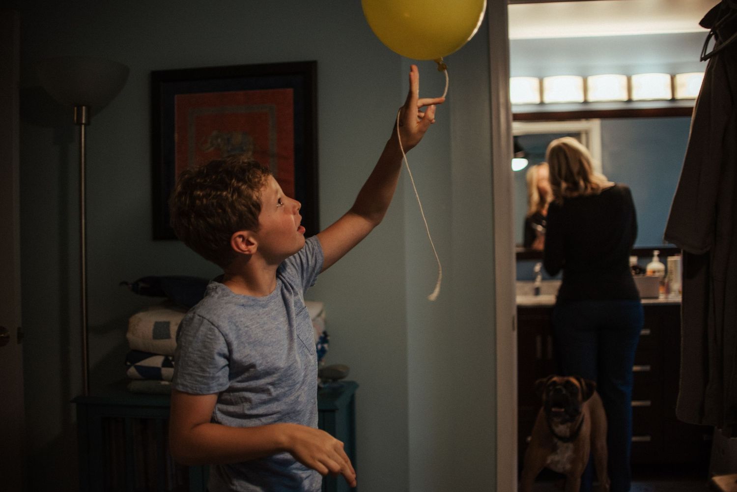 A sequence of photos showing a boy reaching up to catch a yellow balloon floating near a ceiling while his mother gets ready next door.