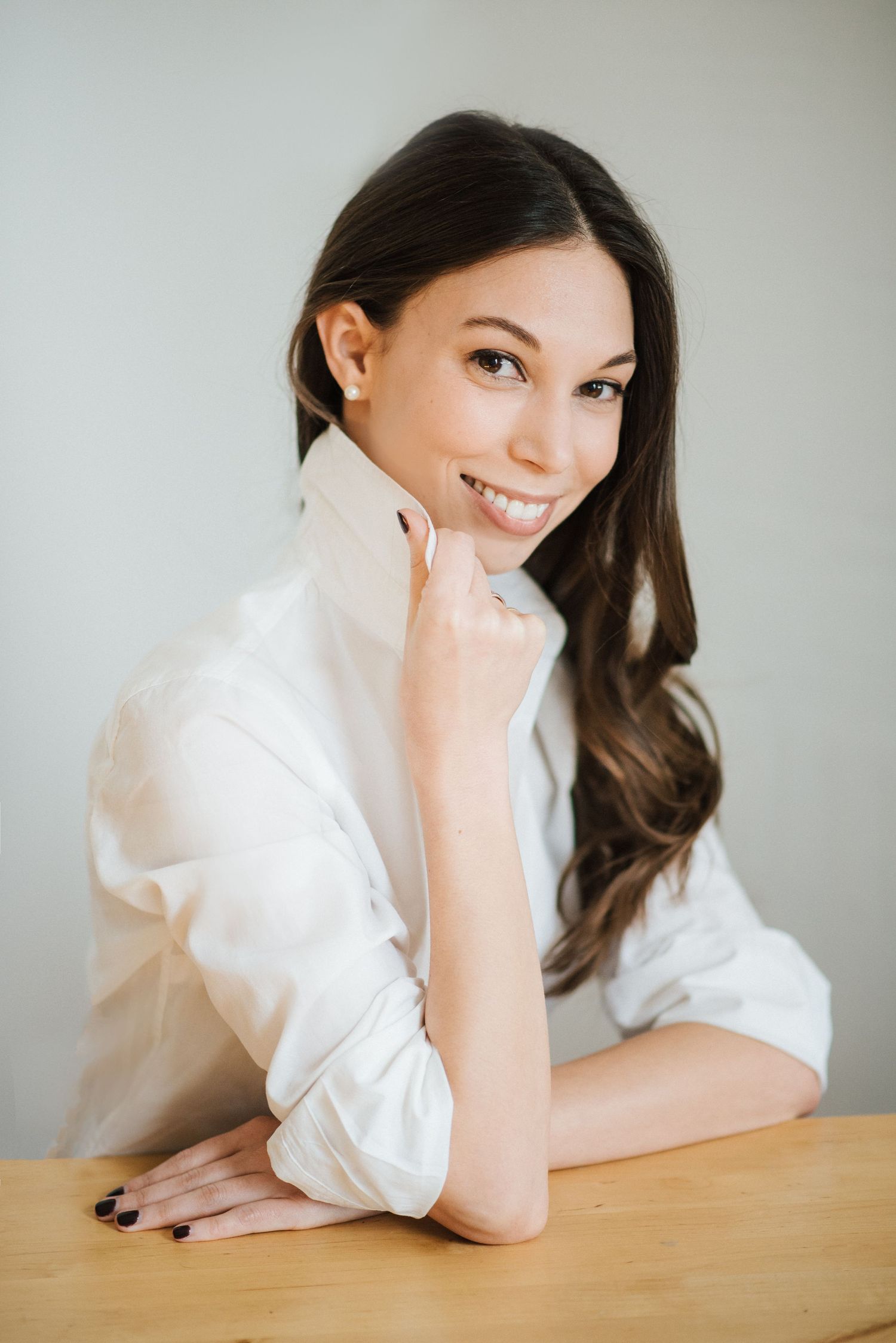 A person in a white blouse rests their head on their hand while leaning on a wooden surface in a series of poses.