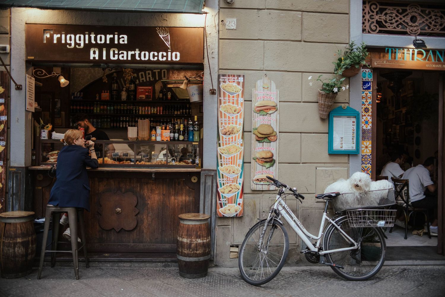 Small Italian tobacco shop storefront with wooden counter and bicycle parked outside on a charming street corner.