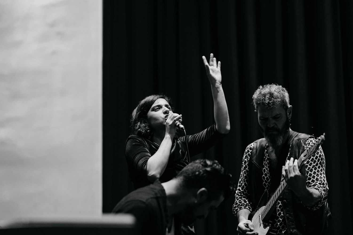 Dramatic black and white photo of dancers performing expressive movements on stage.