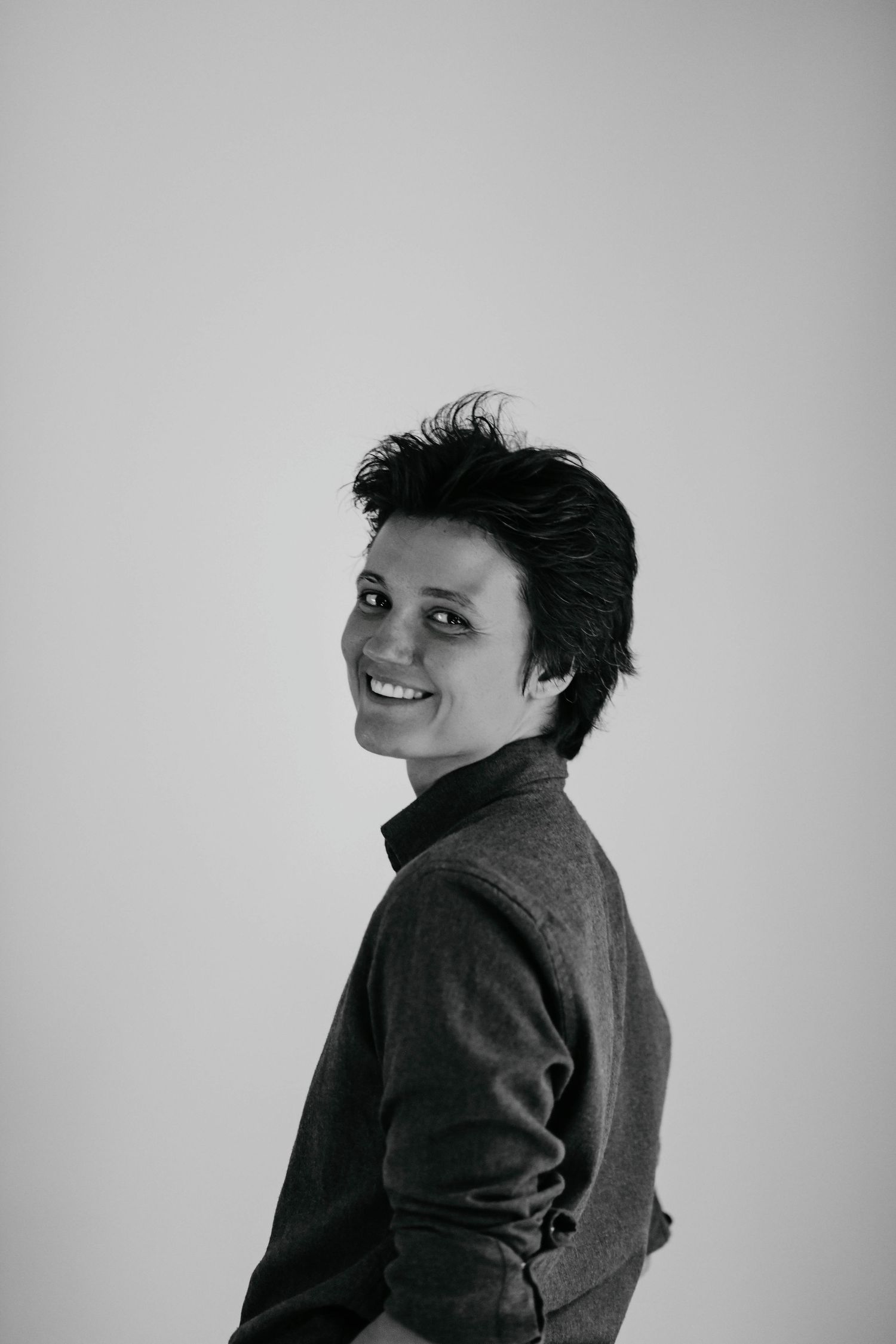 Black and white photo series showing someone in a dark jacket turning and smiling against a light background.