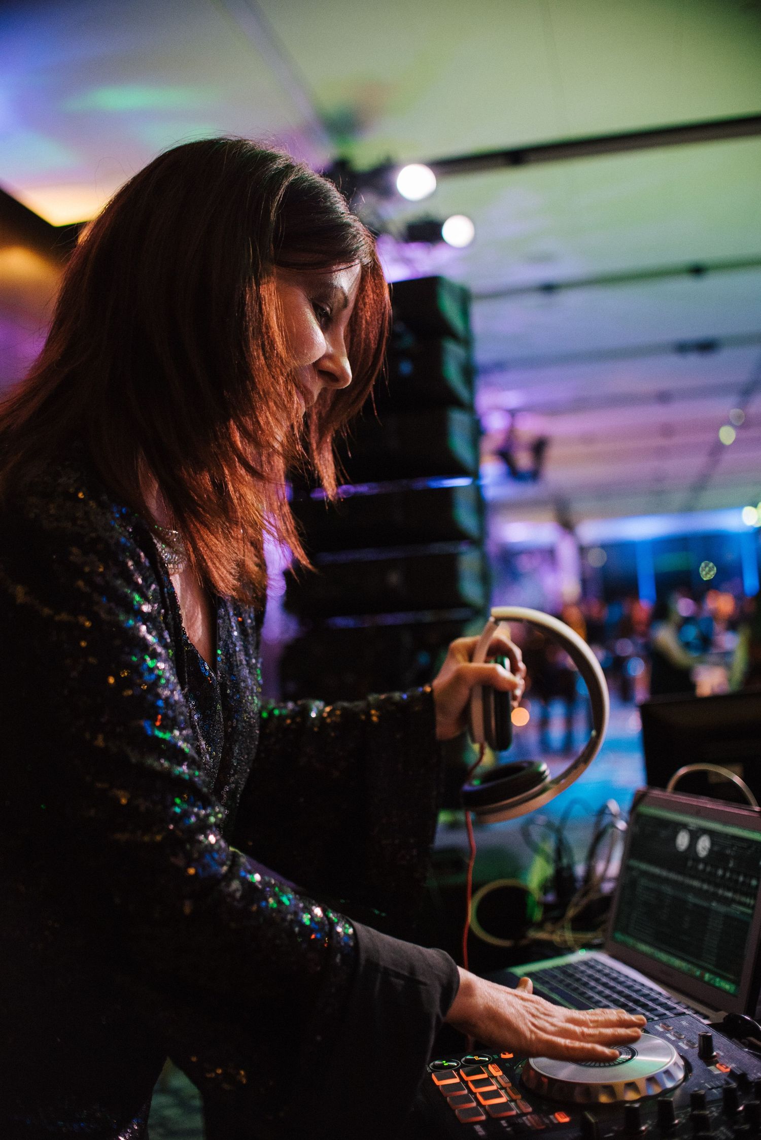 DJ mixing music on turntables with colorful ambient lighting in the background.