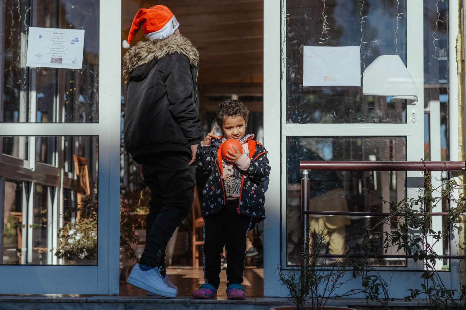People walking past storefronts and holiday decorations in an urban shopping area.