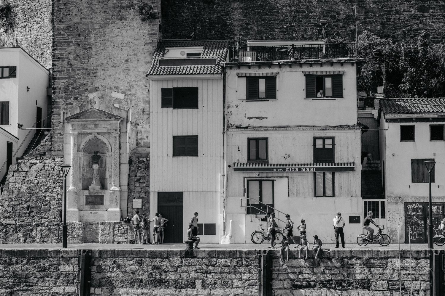 Black and white panoramic cityscape of Florence, Italy showing historic buildings and stone walls along the Arno River.
