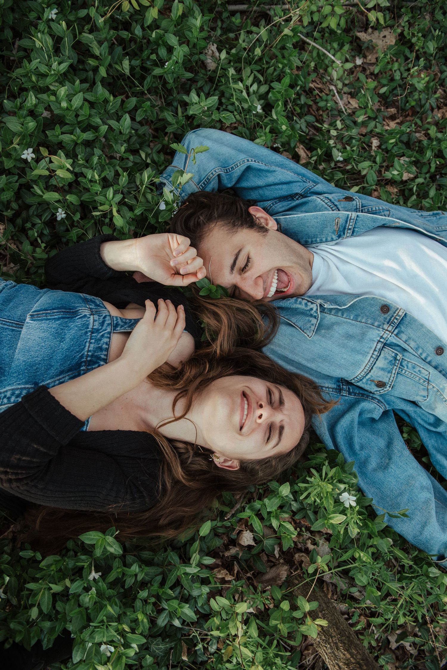 A person wearing denim lies peacefully in green foliage, creating a dreamy outdoor portrait series.