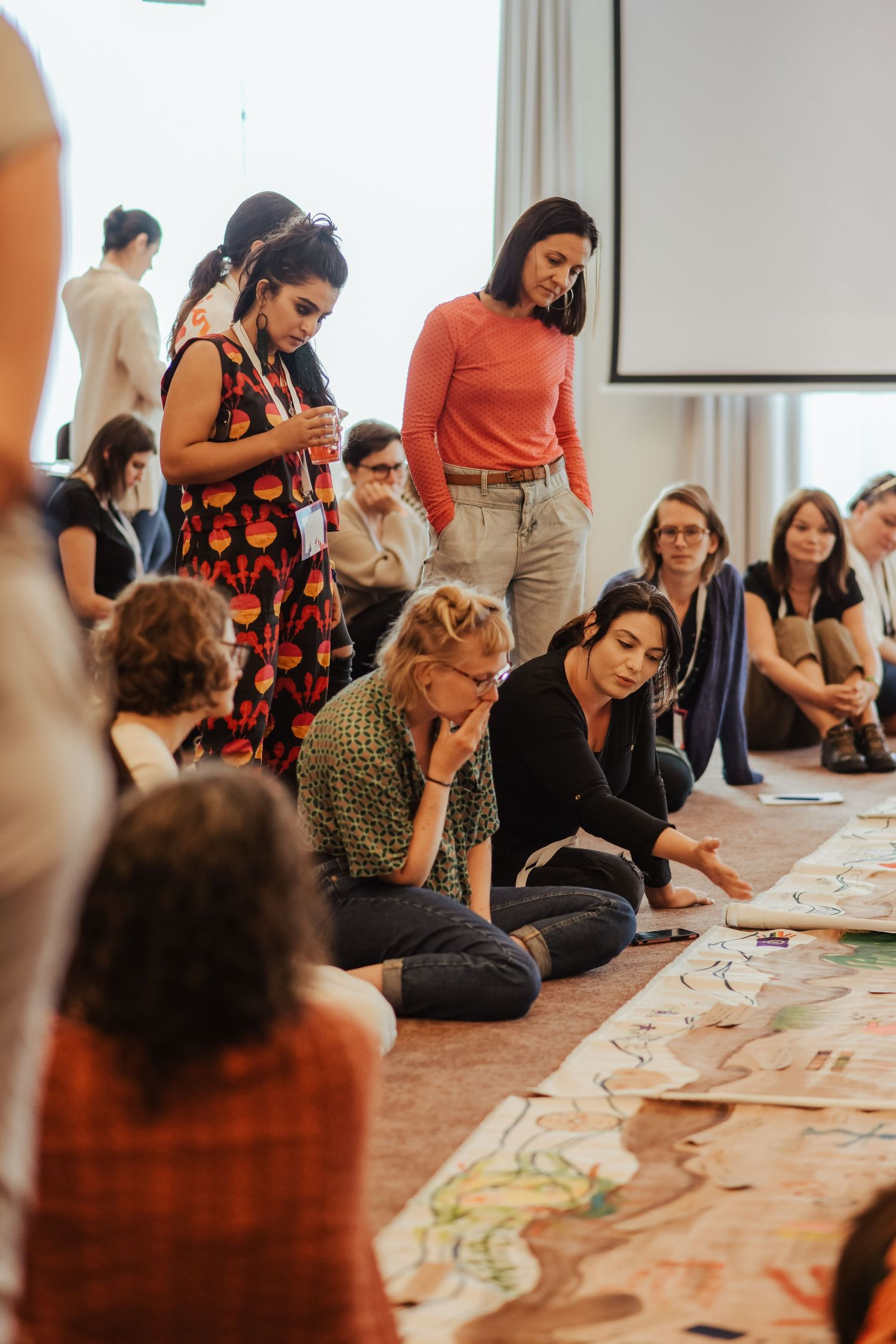 Workshop participants gathered around papers spread on the floor during a collaborative activity.