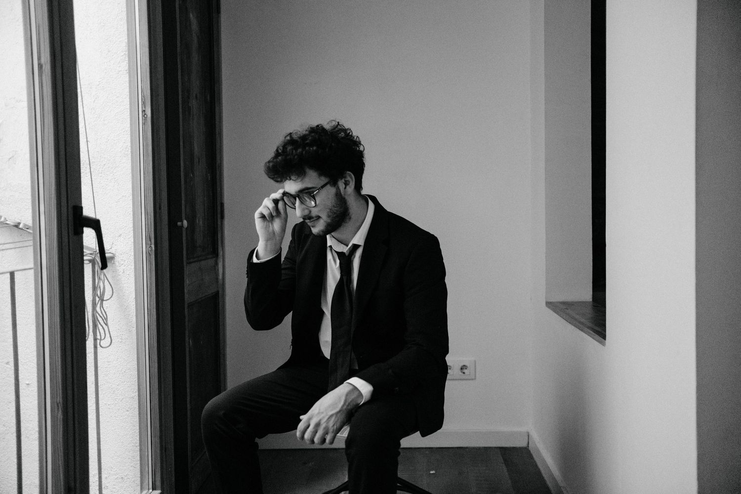 Black and white photo of person in formal attire standing in doorway.