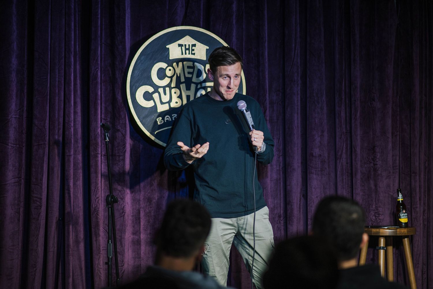 Comedy venue with purple curtains and 'Comedy Club' signage on stage.