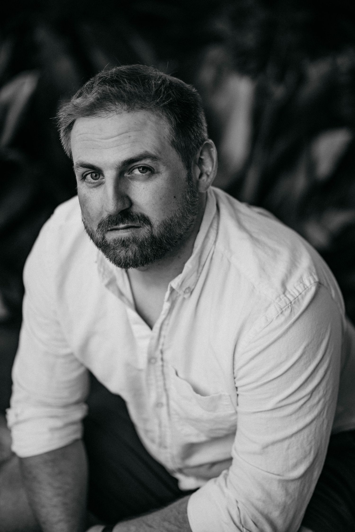 A series of black and white portraits showing a person in a white button-down shirt against a dark background.