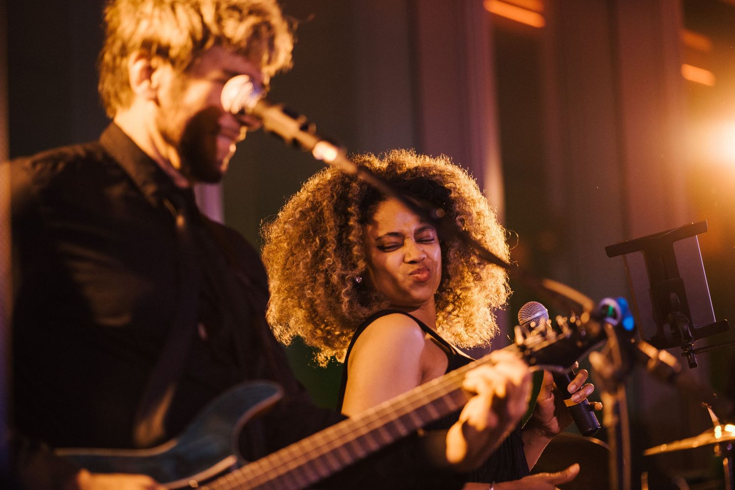 Musicians performing energetically together under warm stage lighting.