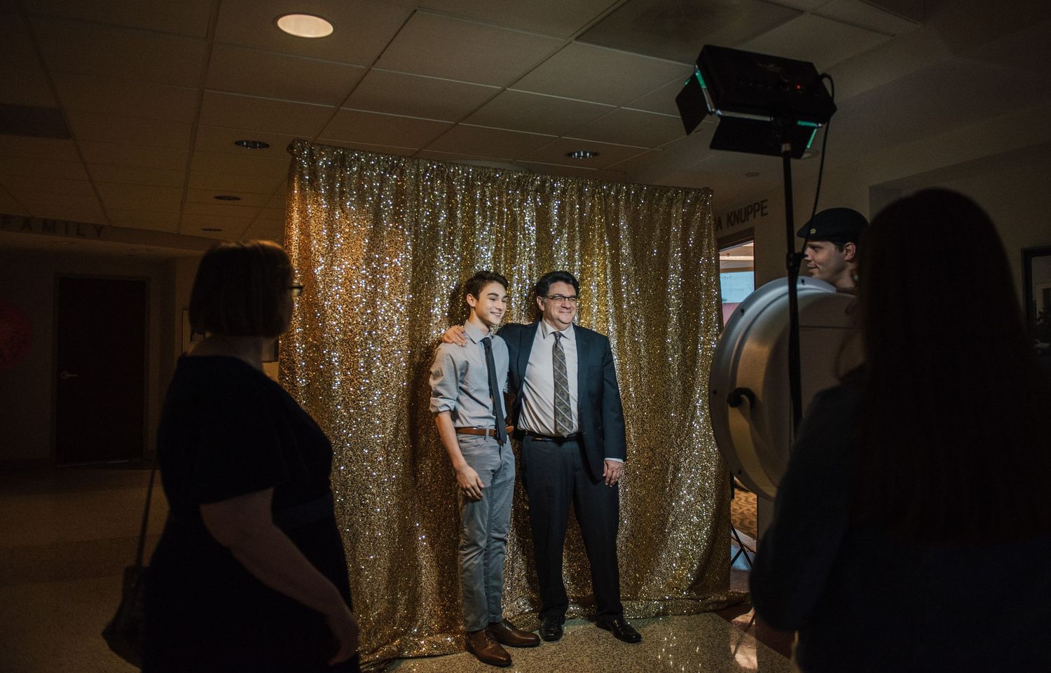 Dark event space with gold sequin backdrop and dramatic lighting for a special occasion.