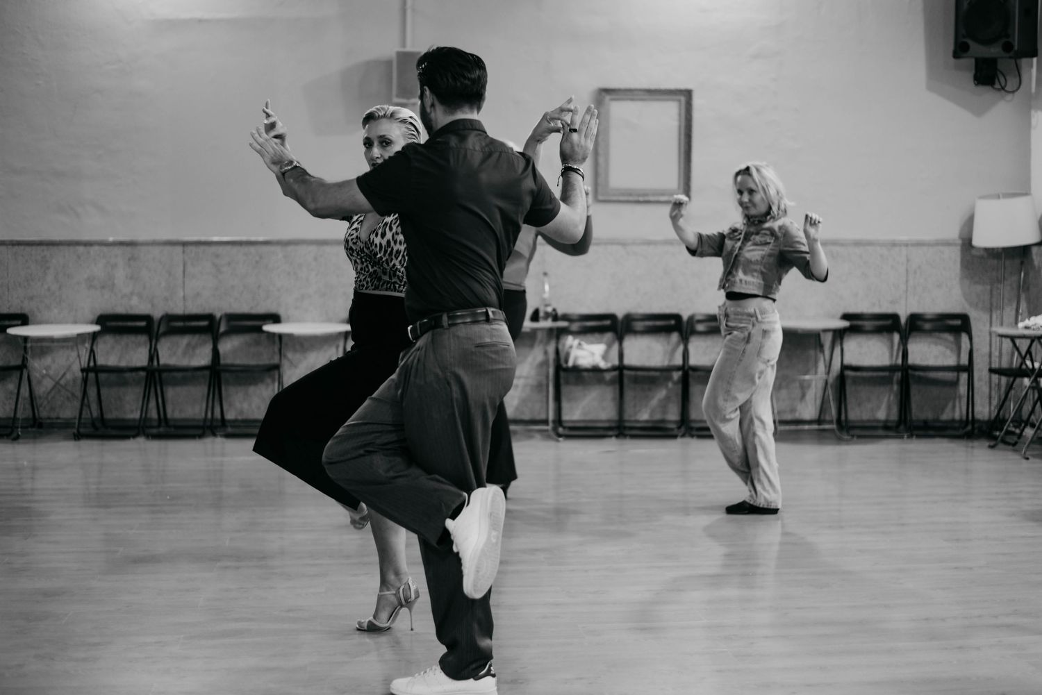Dancers practicing energetic swing dance moves in a bright studio space.