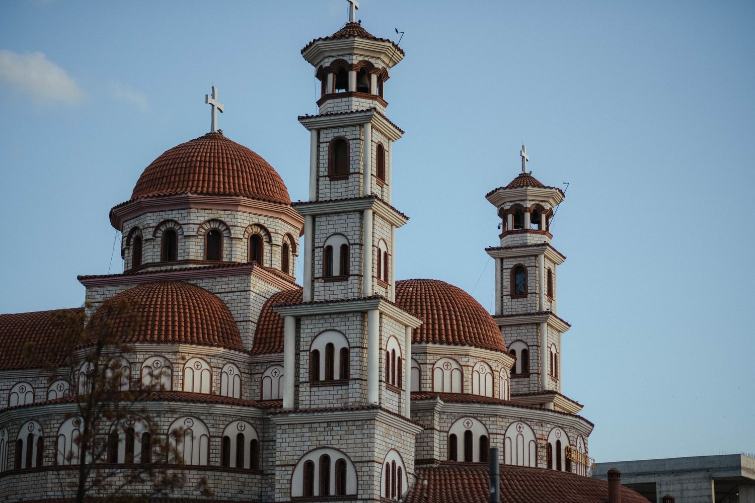 Orthodox church with ornate domed towers and crosses against a blue sky.
