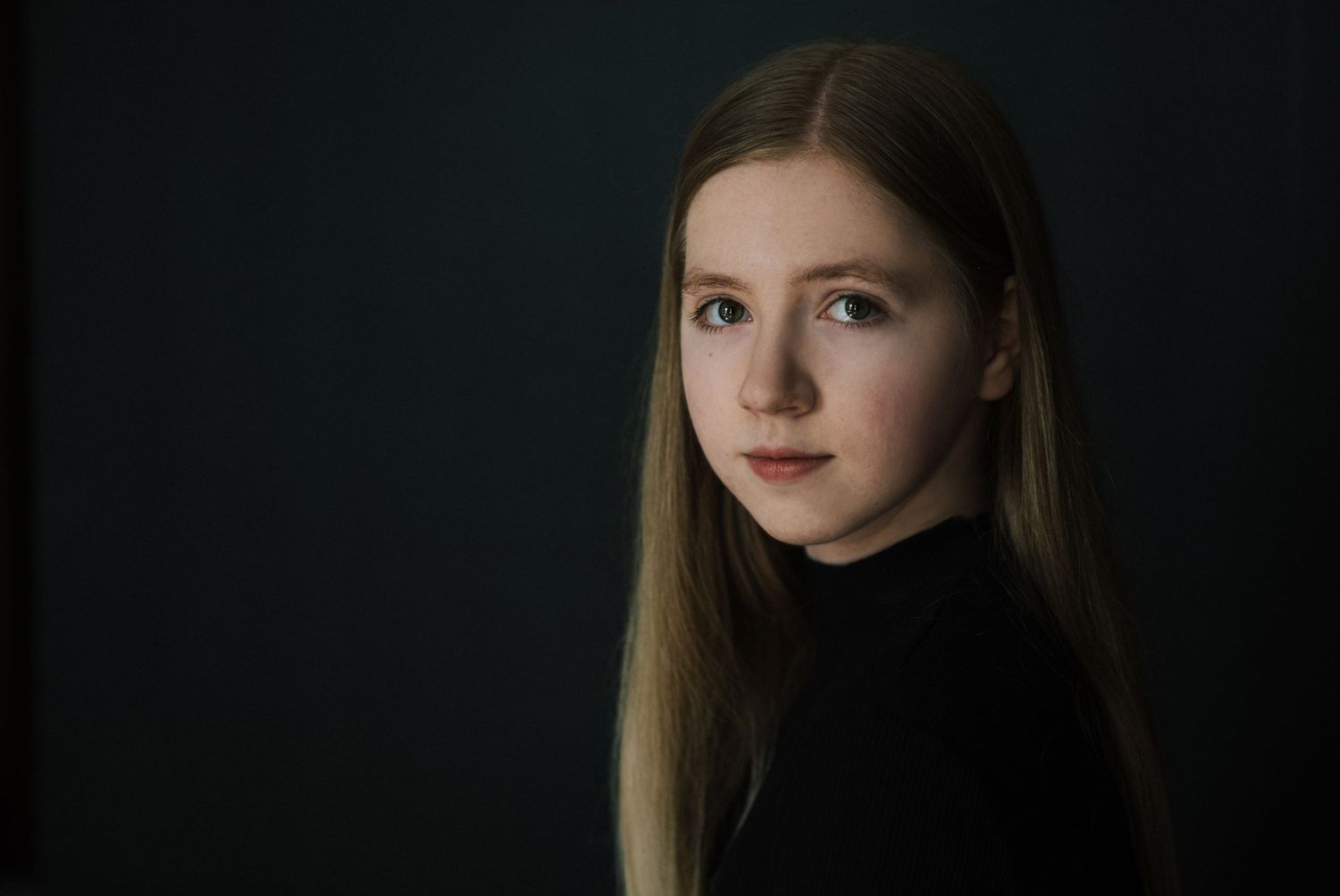 A series of moody portrait photographs in dark lighting shows a person with blonde hair against black backgrounds.