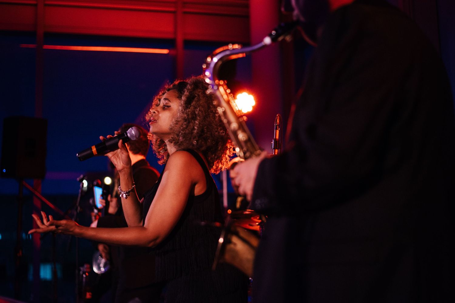 Singer performing passionately on stage with dramatic red lighting.