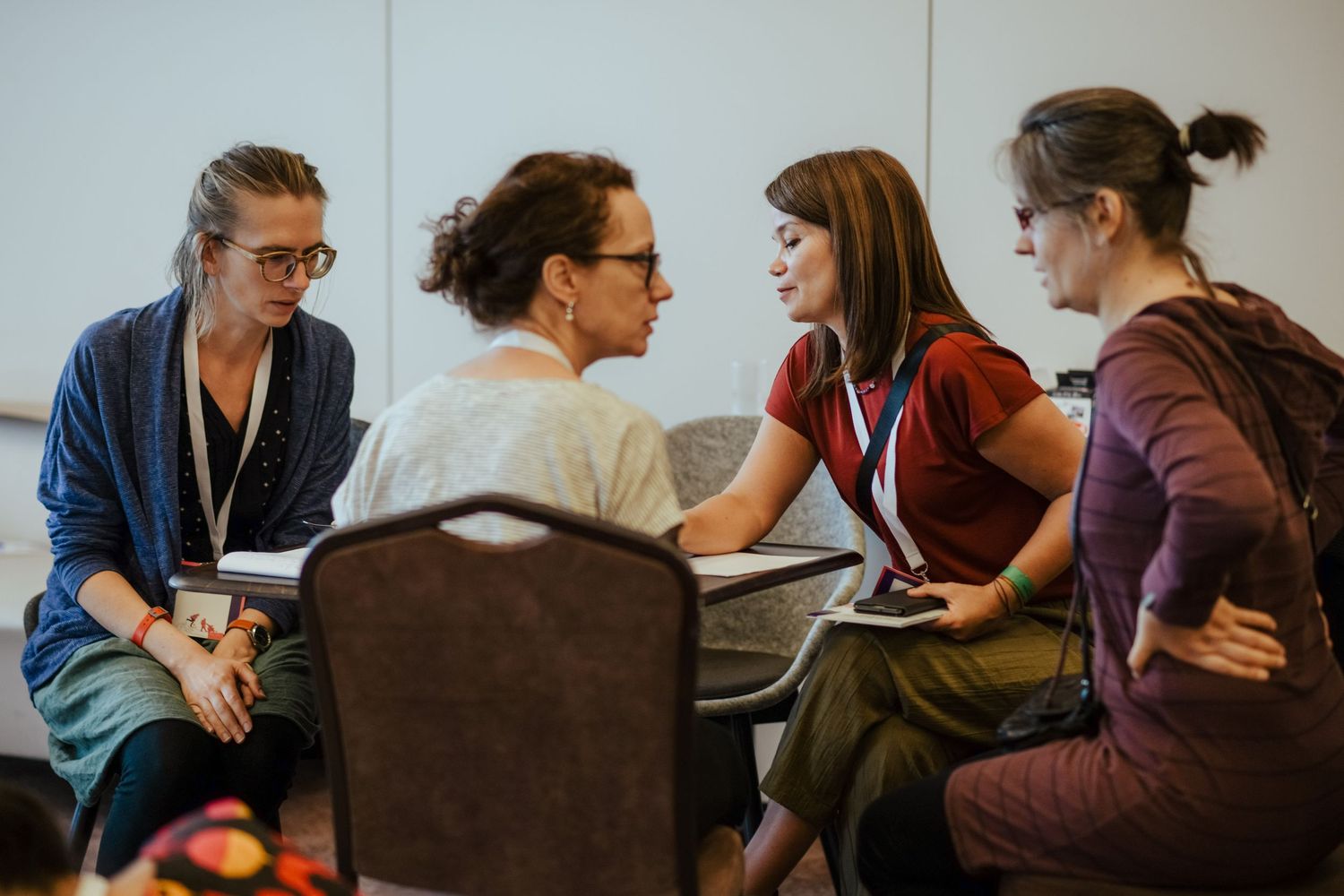 People engaged in discussion while seated in conference chairs during an indoor event.