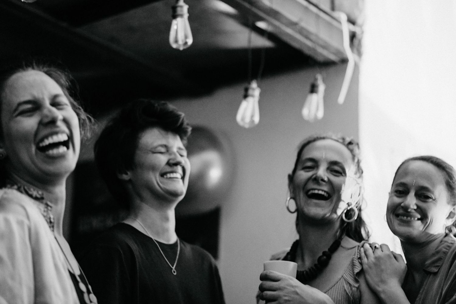 Group laughing together during a social gathering in black and white.