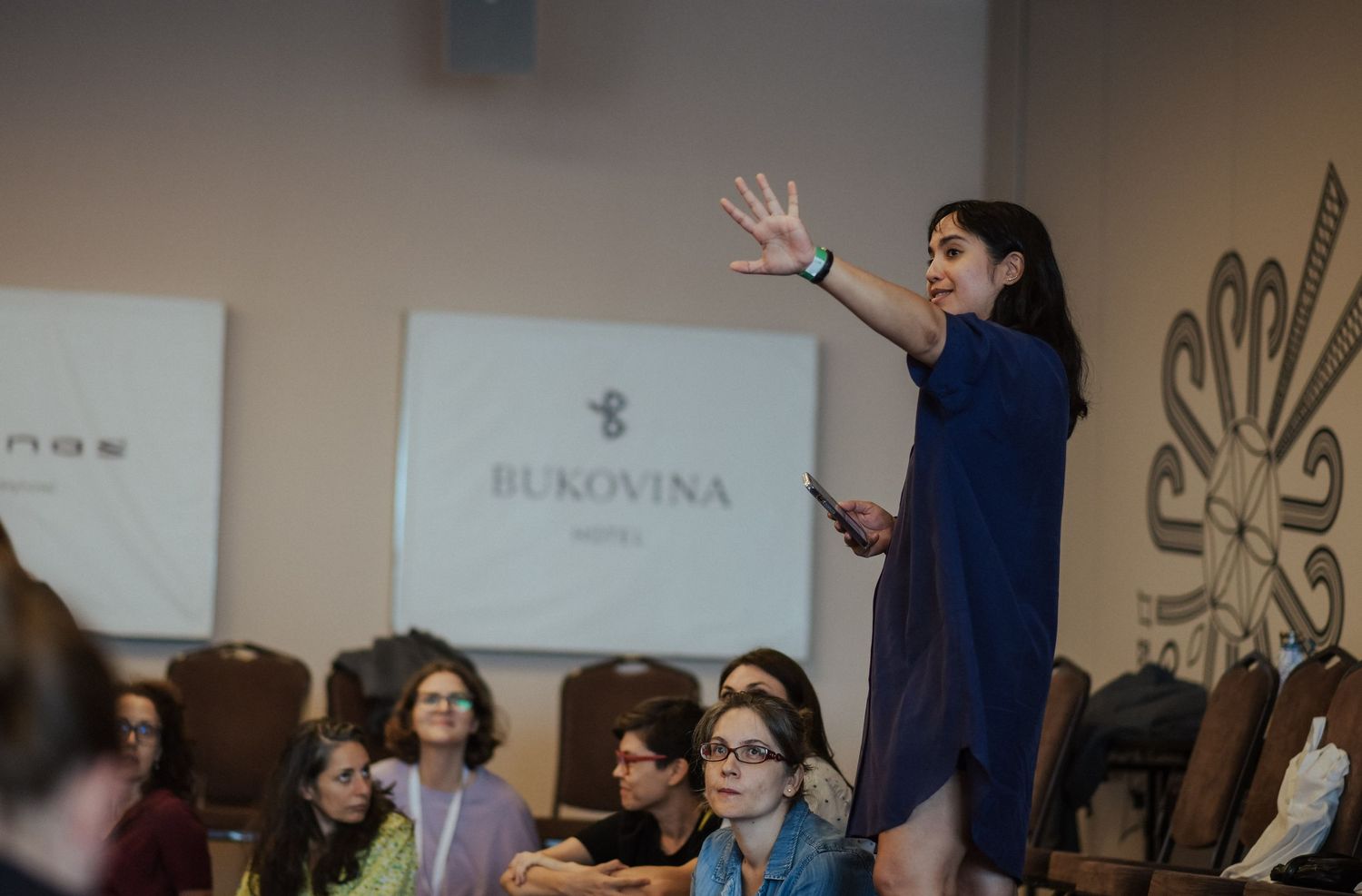 Speaker gesturing enthusiastically during a presentation to an engaged audience.