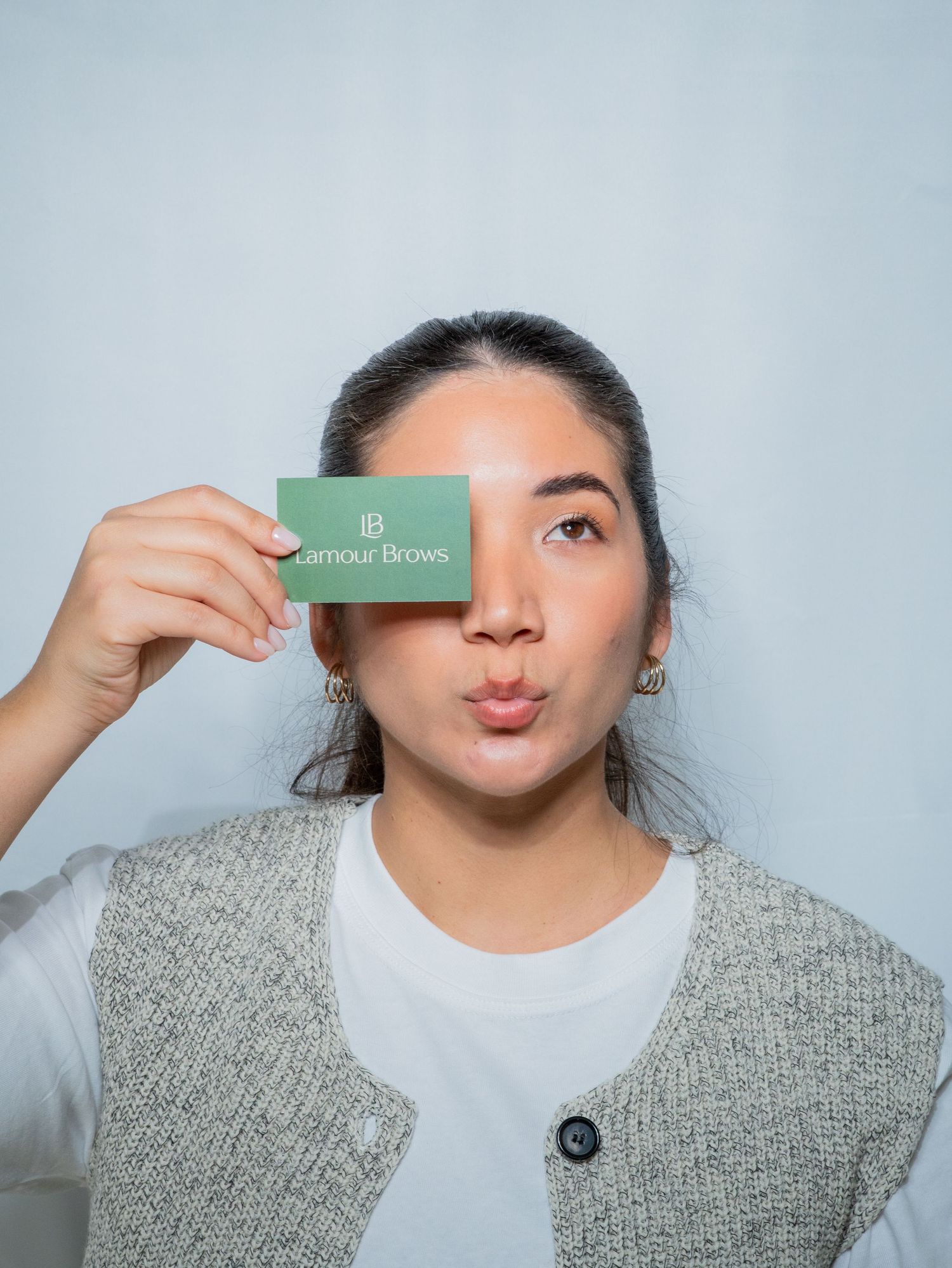 A series of four photos showing someone playfully posing with a small green business card in front of their face.