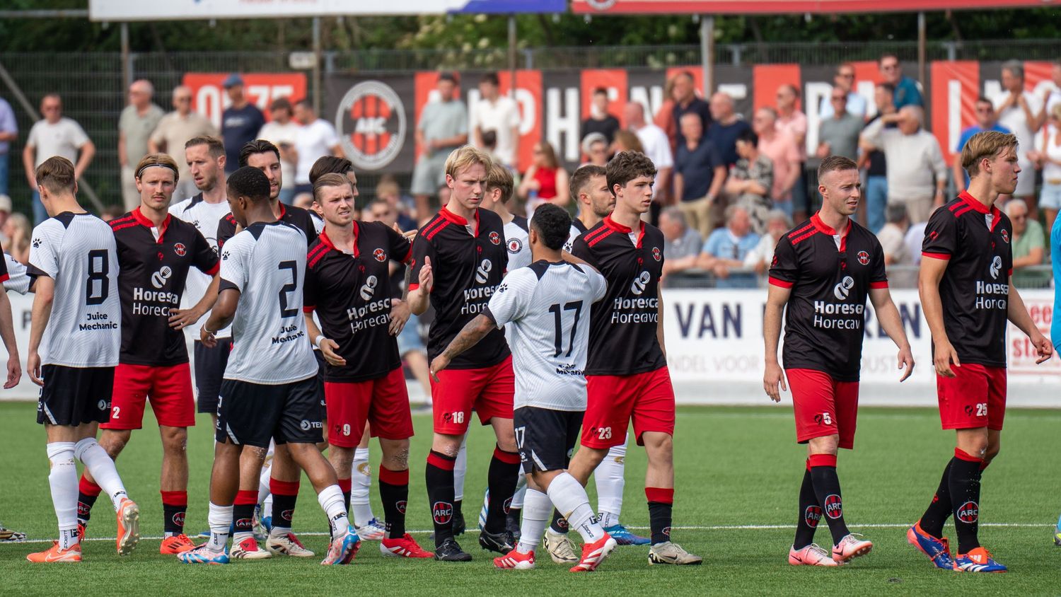 Soccer players from opposing teams shake hands and exchange post-match pleasantries on the field after a game.