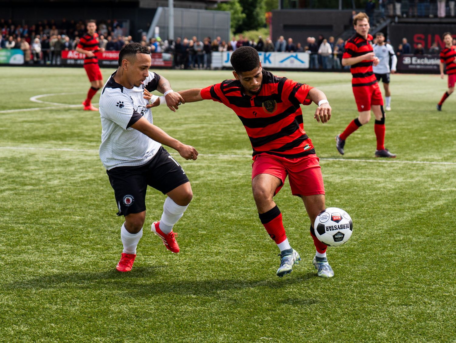 Soccer players compete for possession of the ball during an intense match on a grass field.