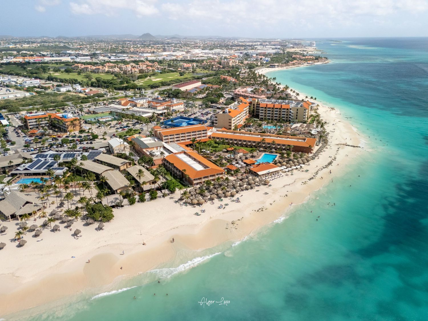 Aerial view of a luxury beachfront resort in Aruba with turquoise Caribbean waters and white sandy beach.