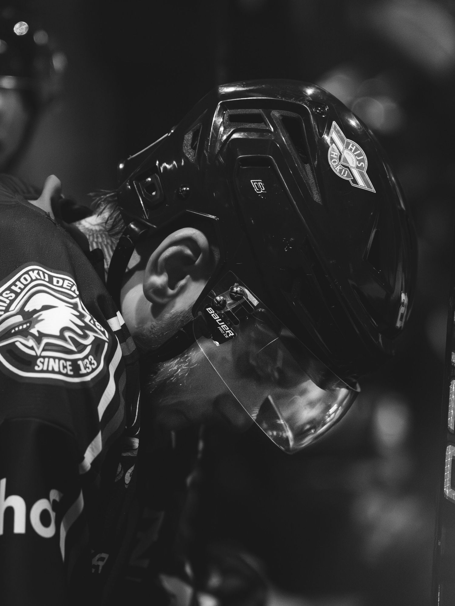 Black and white hockey players celebrate together in a dark arena after scoring a goal.