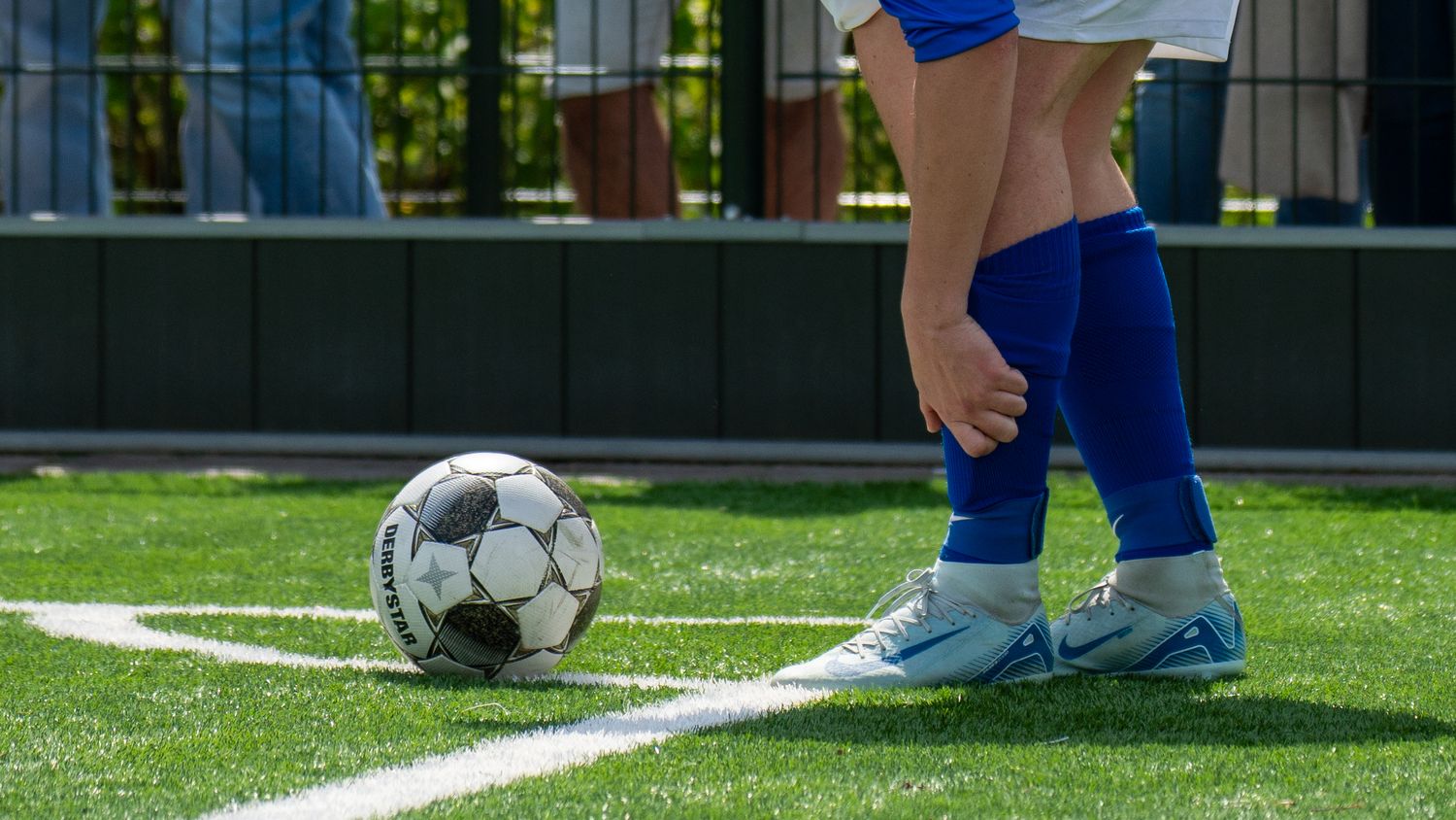 Close-up of soccer player's feet with ball on artificial turf sideline.