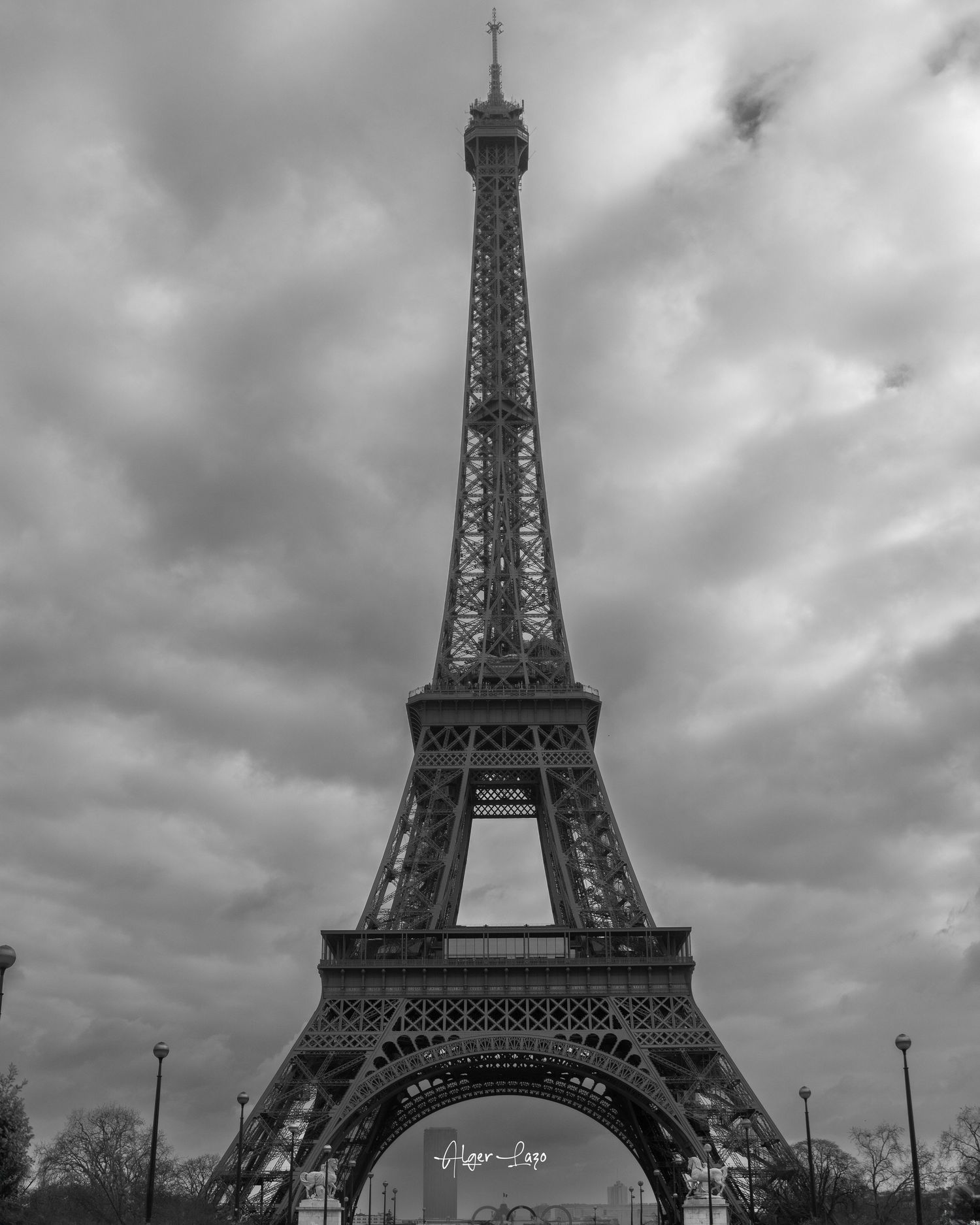 Black and white photo of the Eiffel Tower in Paris under dramatic cloudy skies.