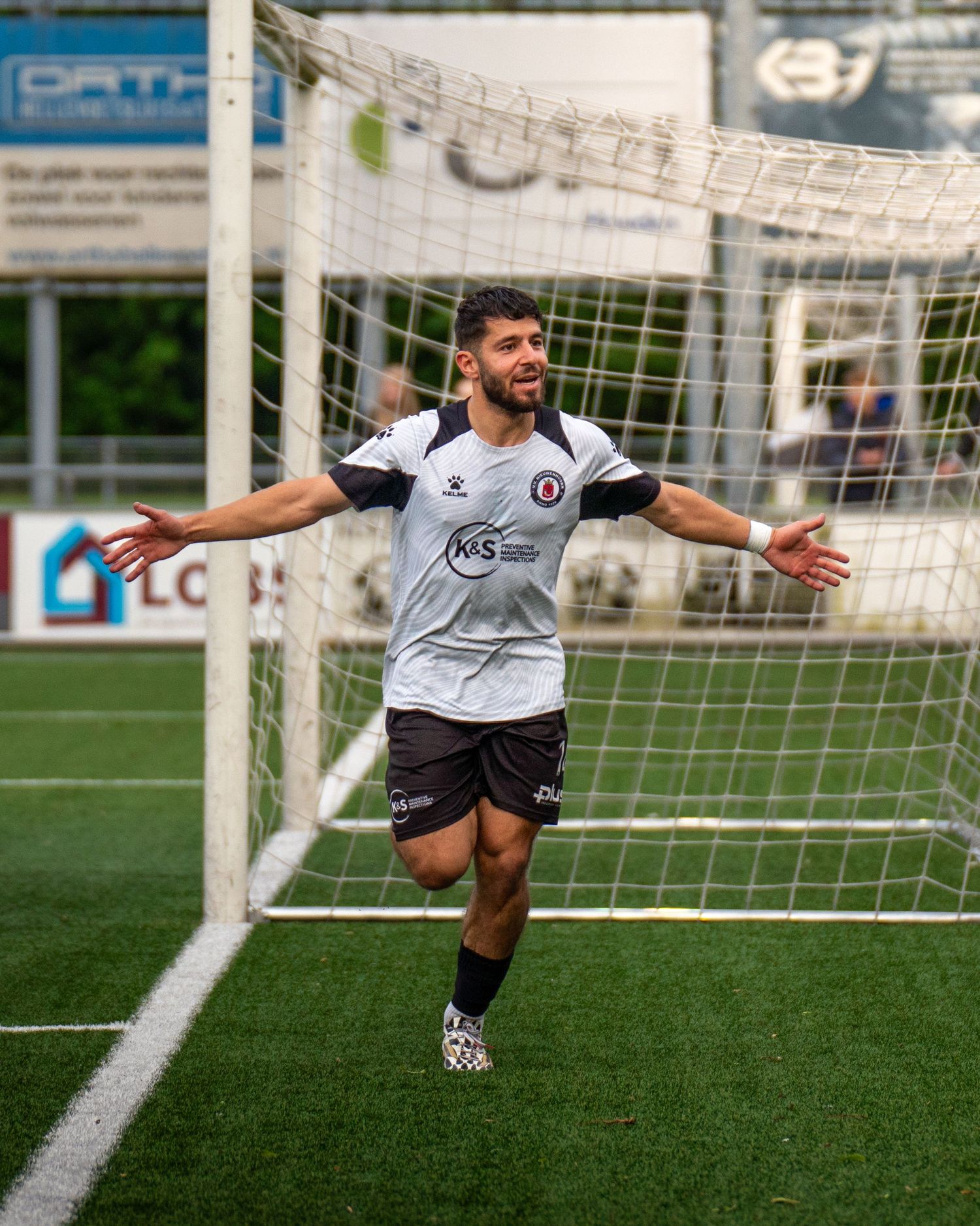 Soccer player in white jersey diving towards goal post on artificial turf field during game action.