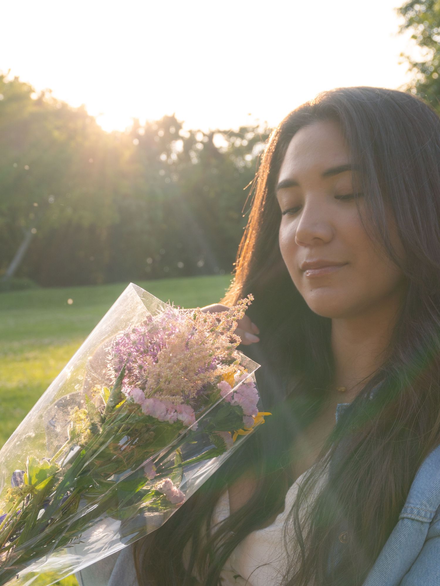 A person with long dark hair poses outdoors with pink flowers at golden hour in a series of dreamy portraits.