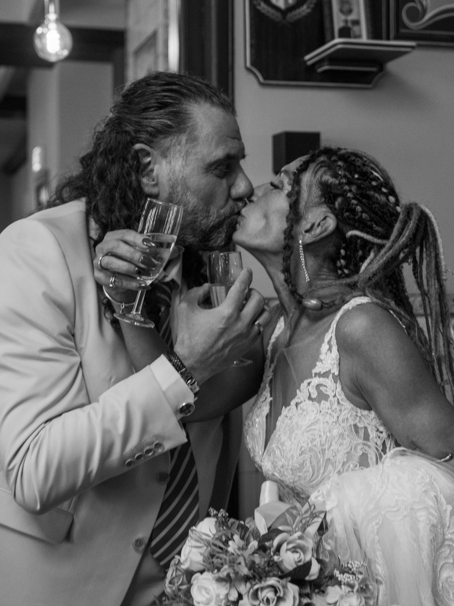 A couple shares an intimate kiss during their wedding celebration in black and white photography.