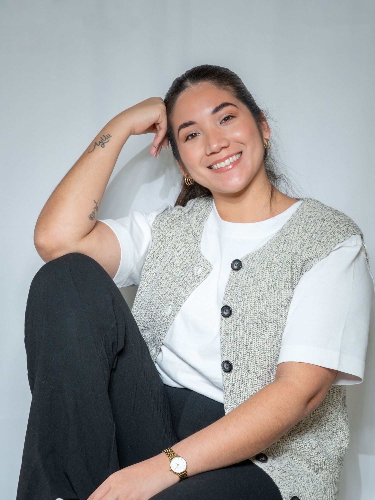 A person in a white t-shirt and gray vest poses casually against a light background in a photo series.