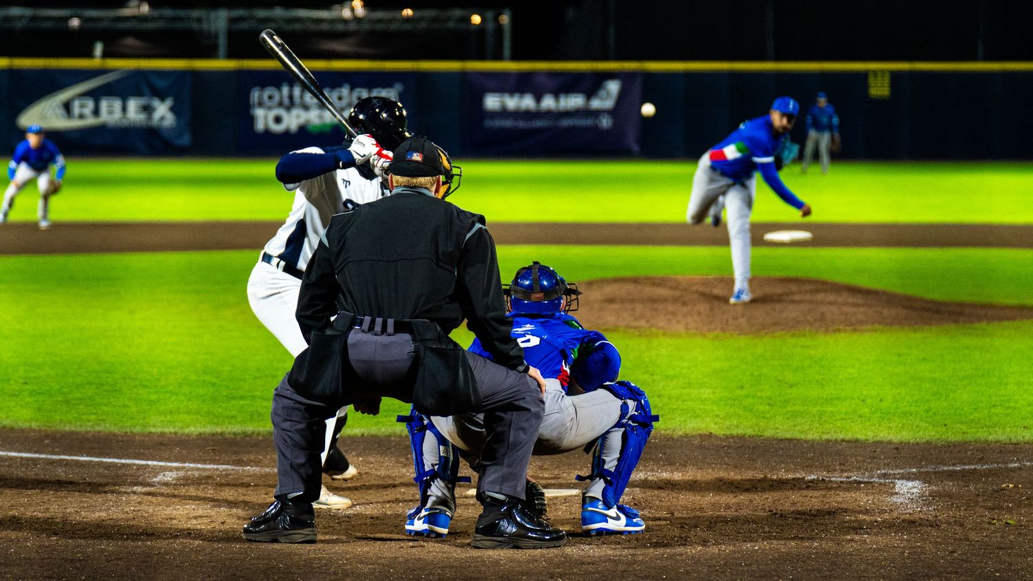 Baseball player slides into home plate during an intense game while catcher awaits with ball in hand.