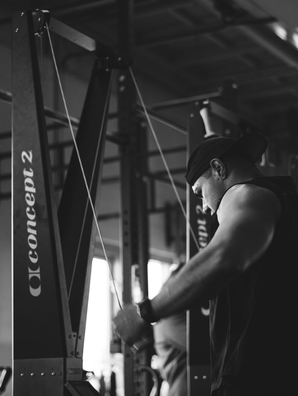 Black and white photo of someone working out on a Concept2 rowing machine in a dimly lit gym.
