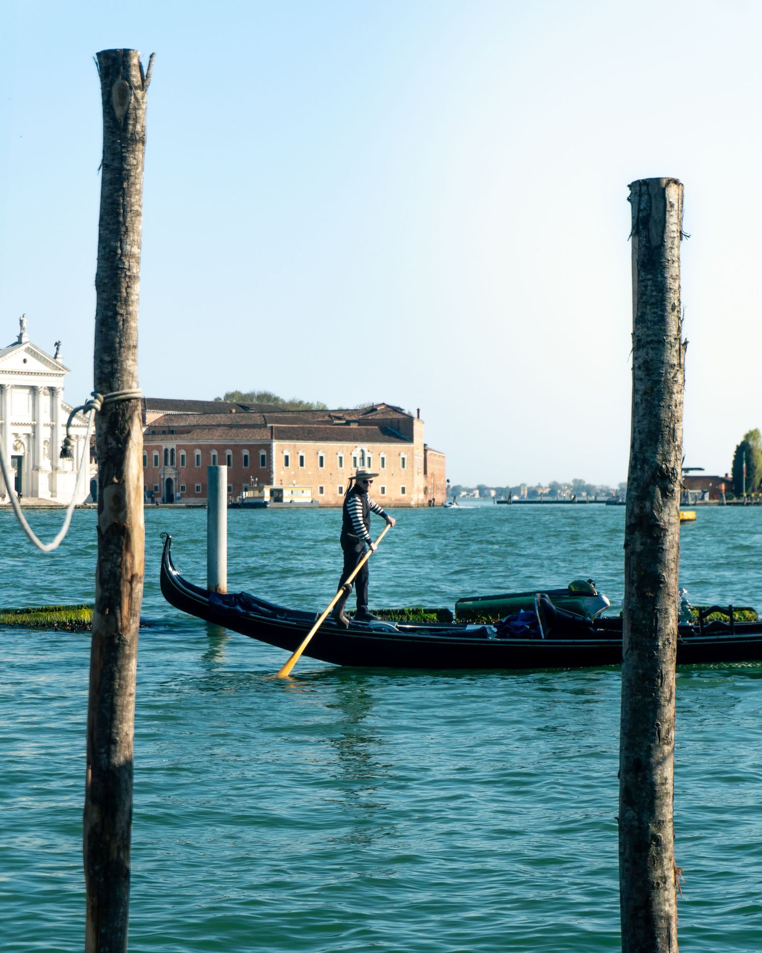 A gondolier navigates a traditional black gondola through Venice's Grand Canal with historic buildings in the background.