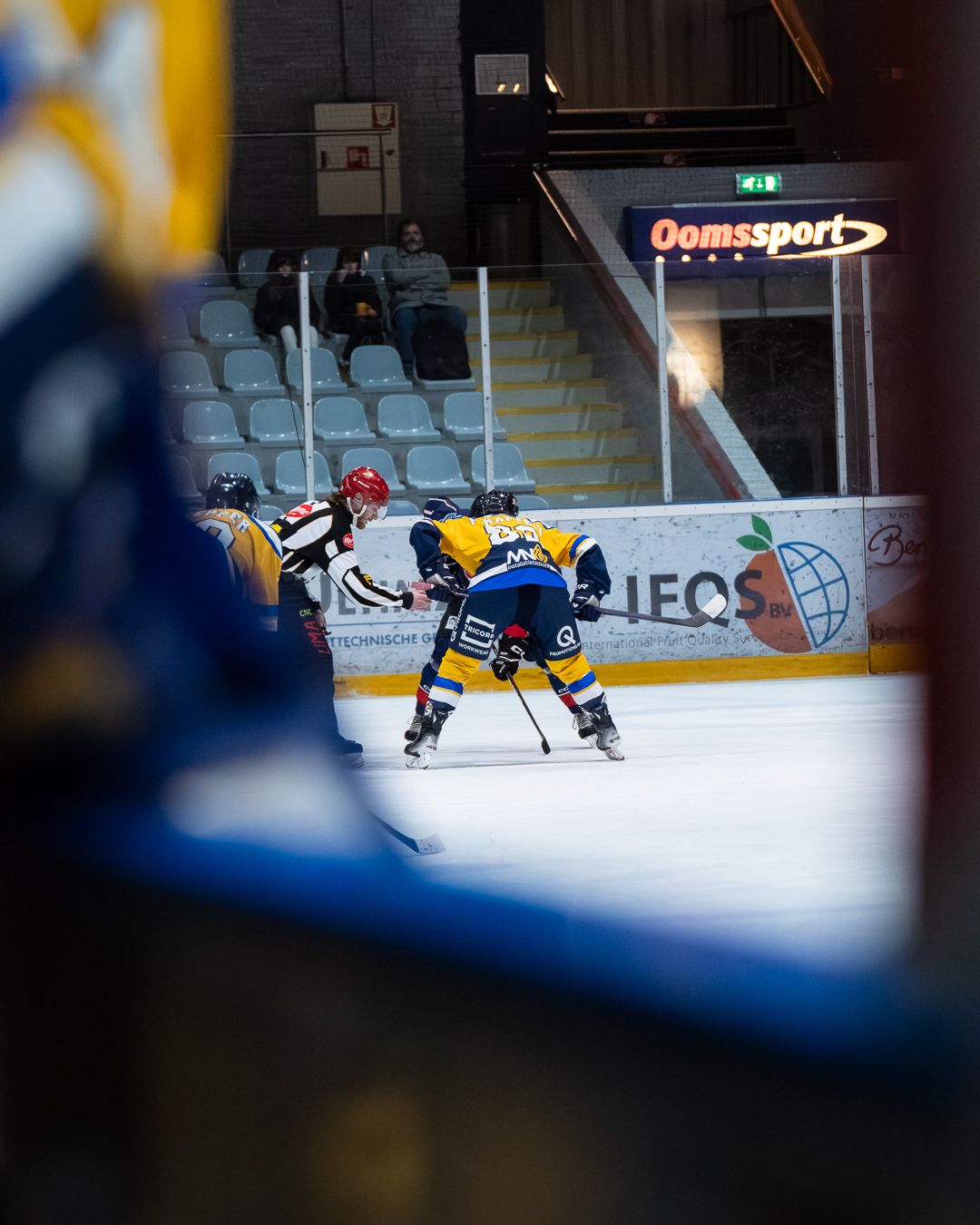 Hockey players in blue and yellow jerseys compete for the puck during an intense ice hockey match.