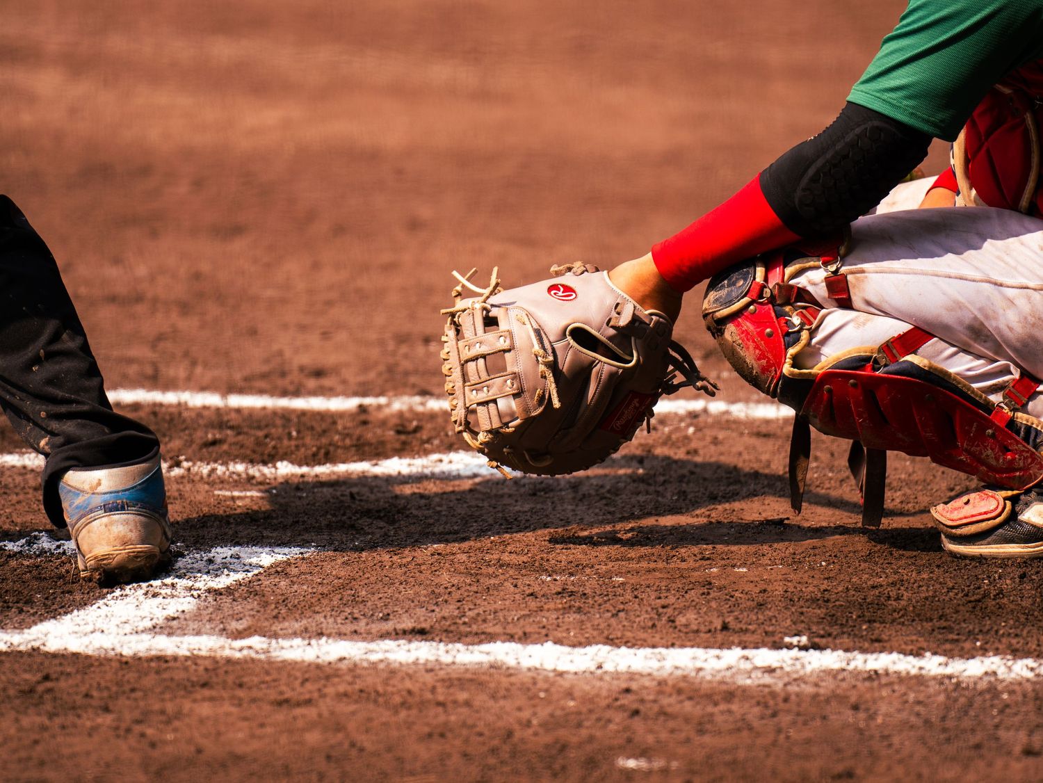 A sequence of baseball cleats sliding into home plate during a baseball game on the dirt infield.