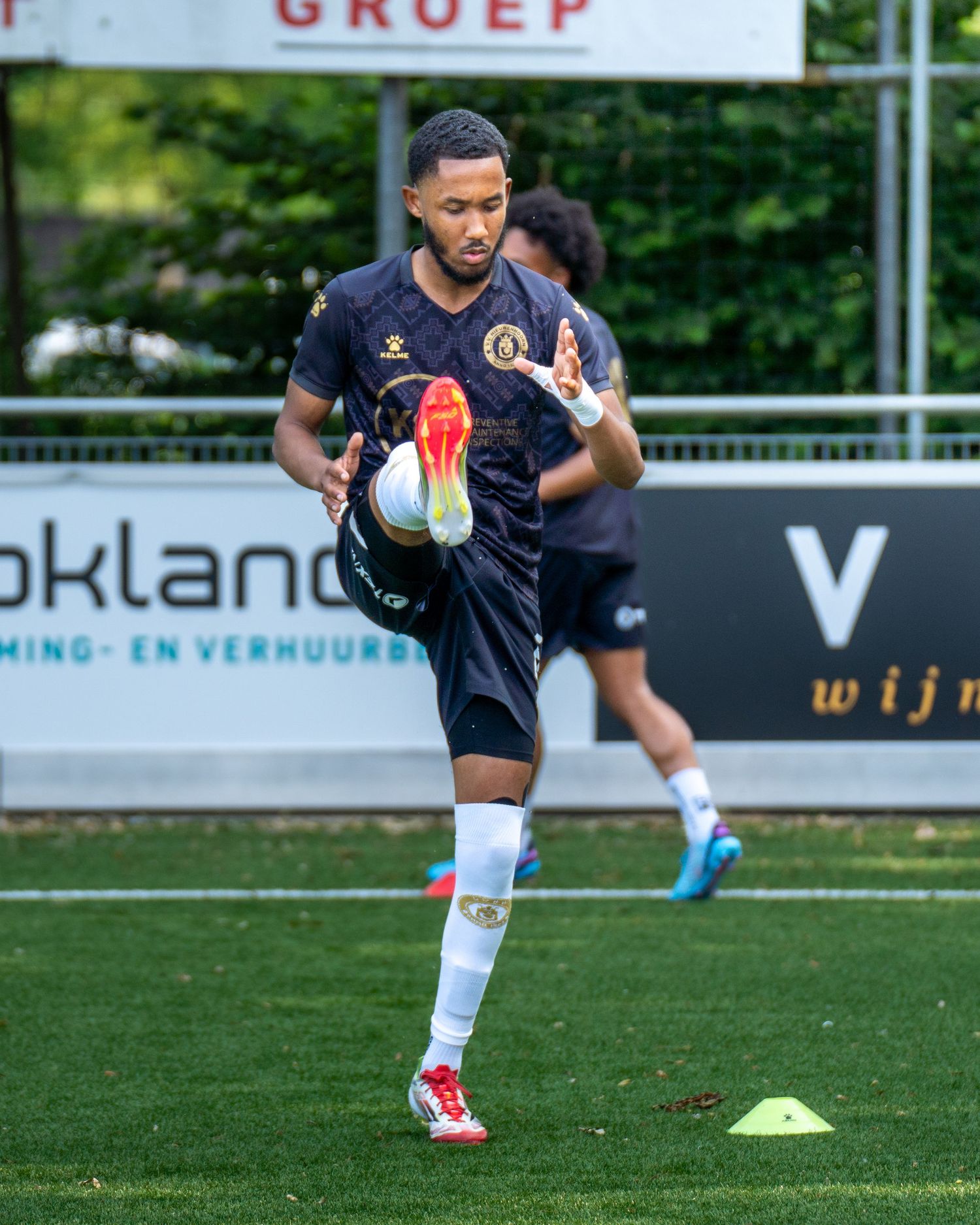 Soccer player performs agility drills around orange cones during outdoor training session on grass field.