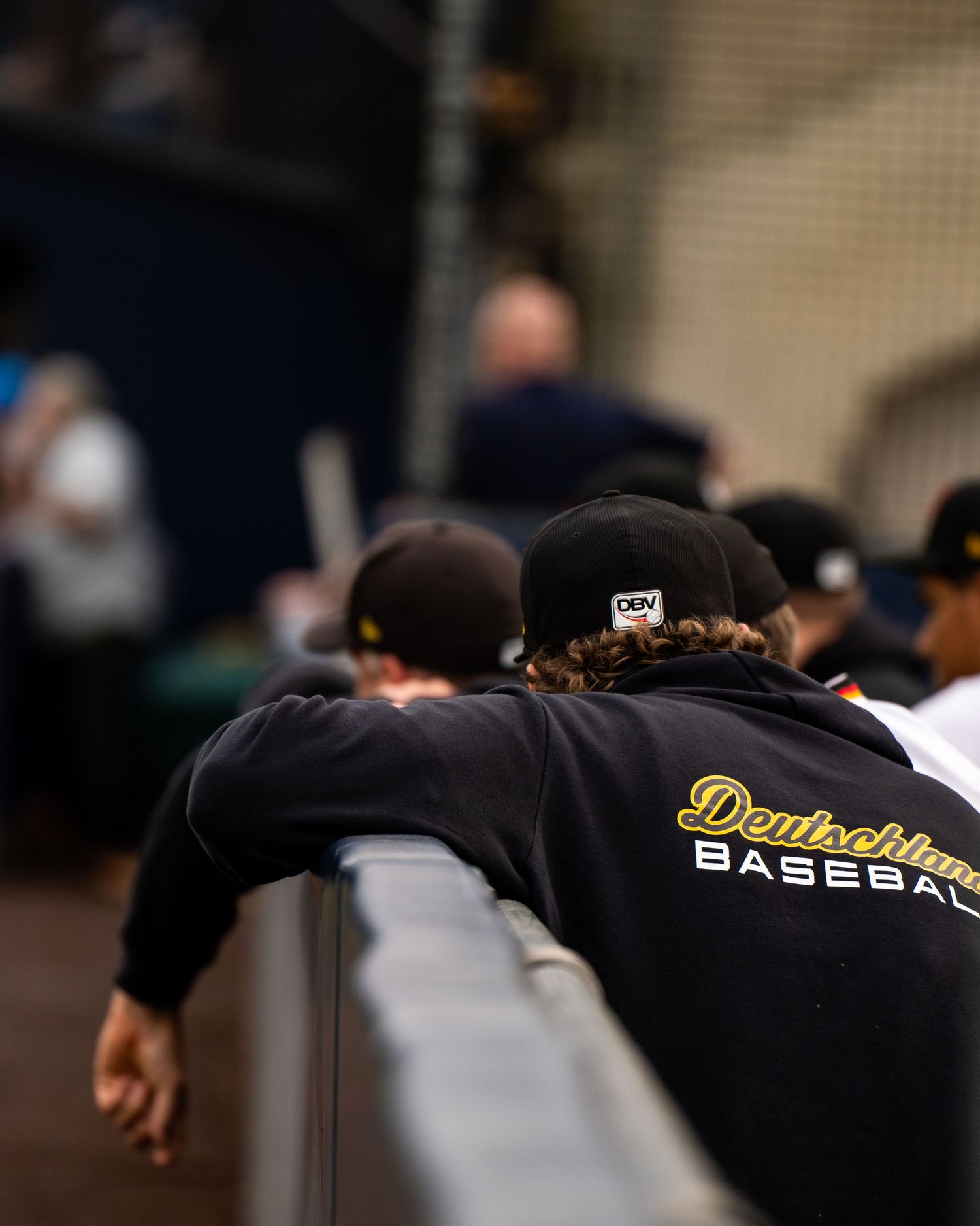 A line of baseball players in dark uniforms huddle together during a game or practice session.