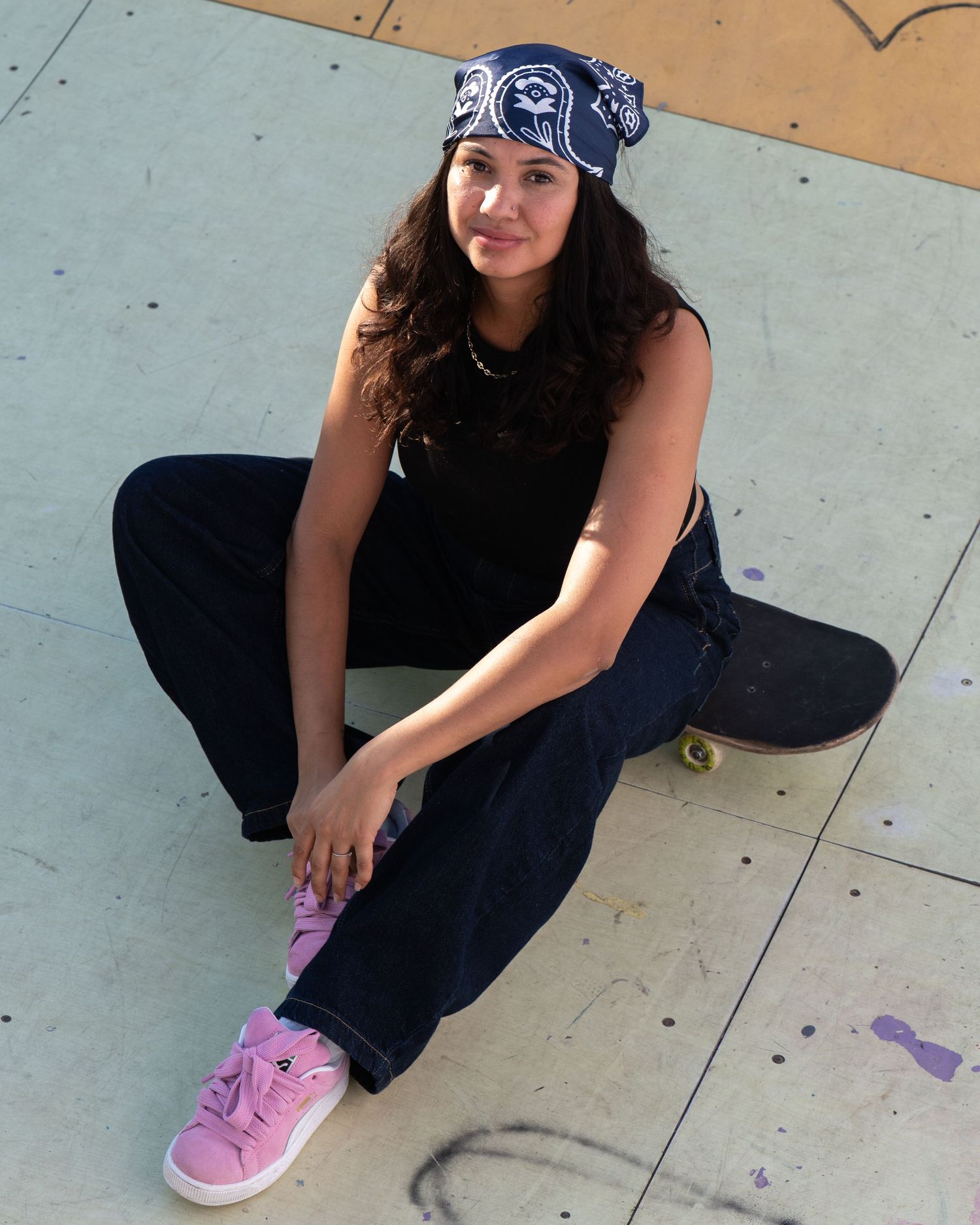 Person in black pants and pink sneakers crouches down on a concrete surface with purple footprints visible.