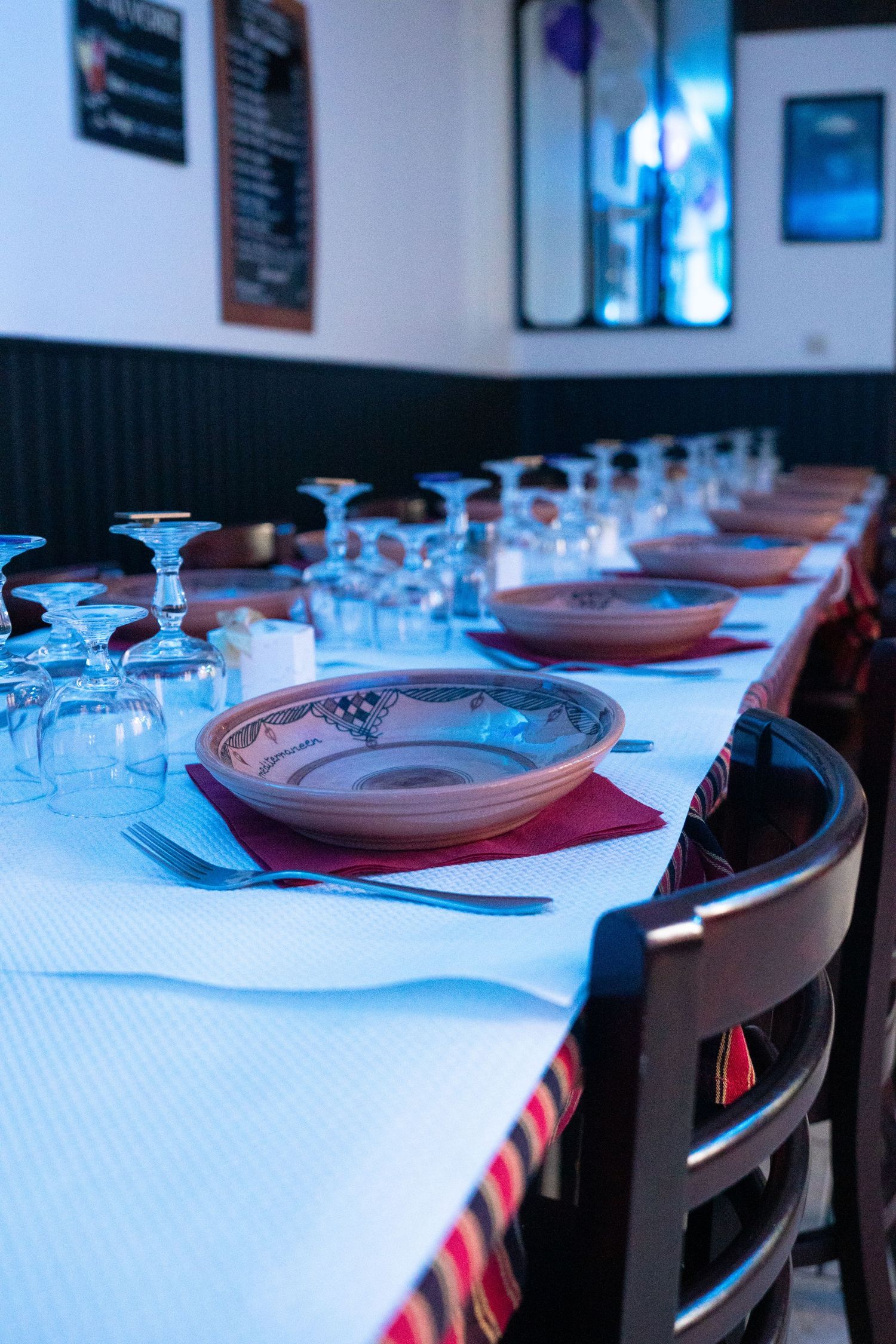 Restaurant table set for formal dinner with blue lighting and white tablecloth.