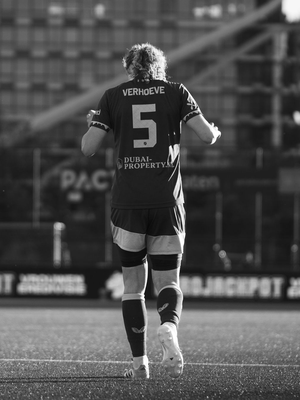 Black and white photo of soccer player Verhoeve wearing number 5 jersey with Dubai Property sponsor running on field.
