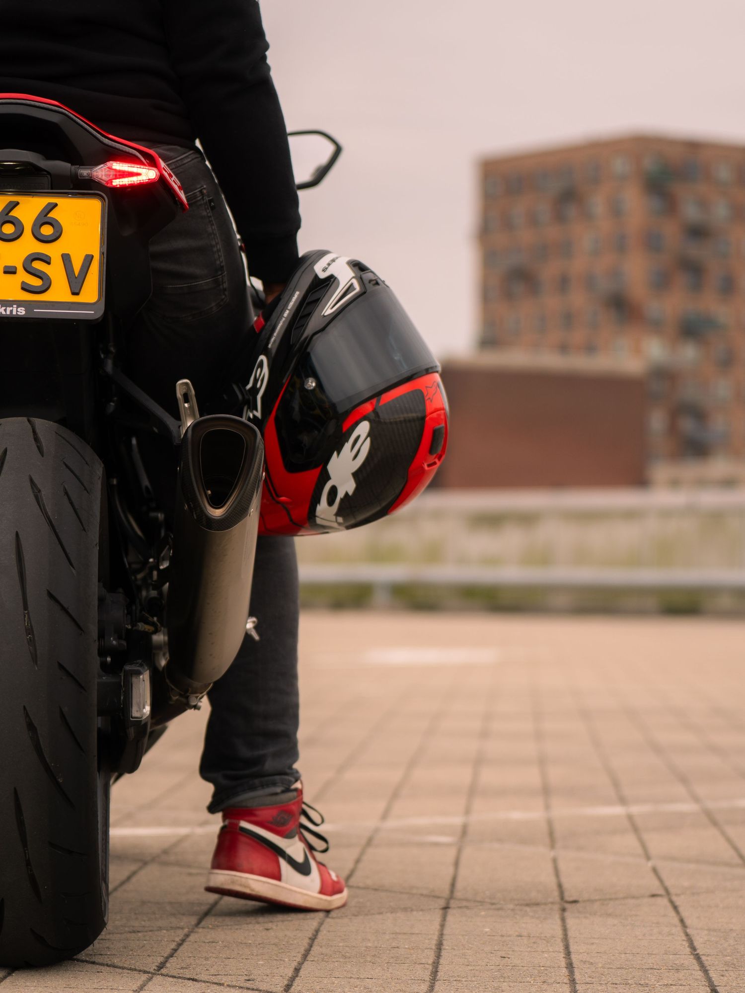 Close-up view of motorcycle boots and tires on a textured stone pavement showing multiple angles and details.