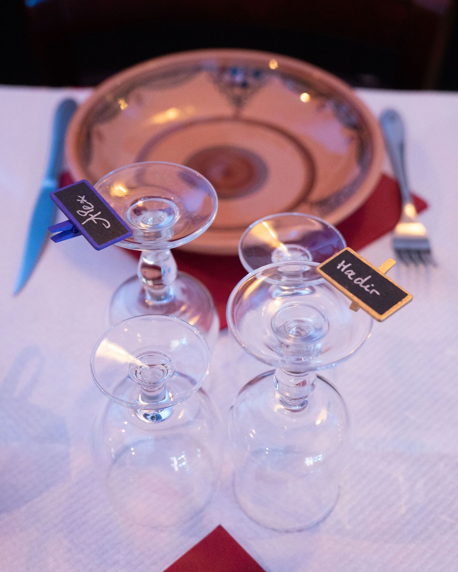 Crystal wine glasses arranged on a white tablecloth with red accents in a restaurant setting.