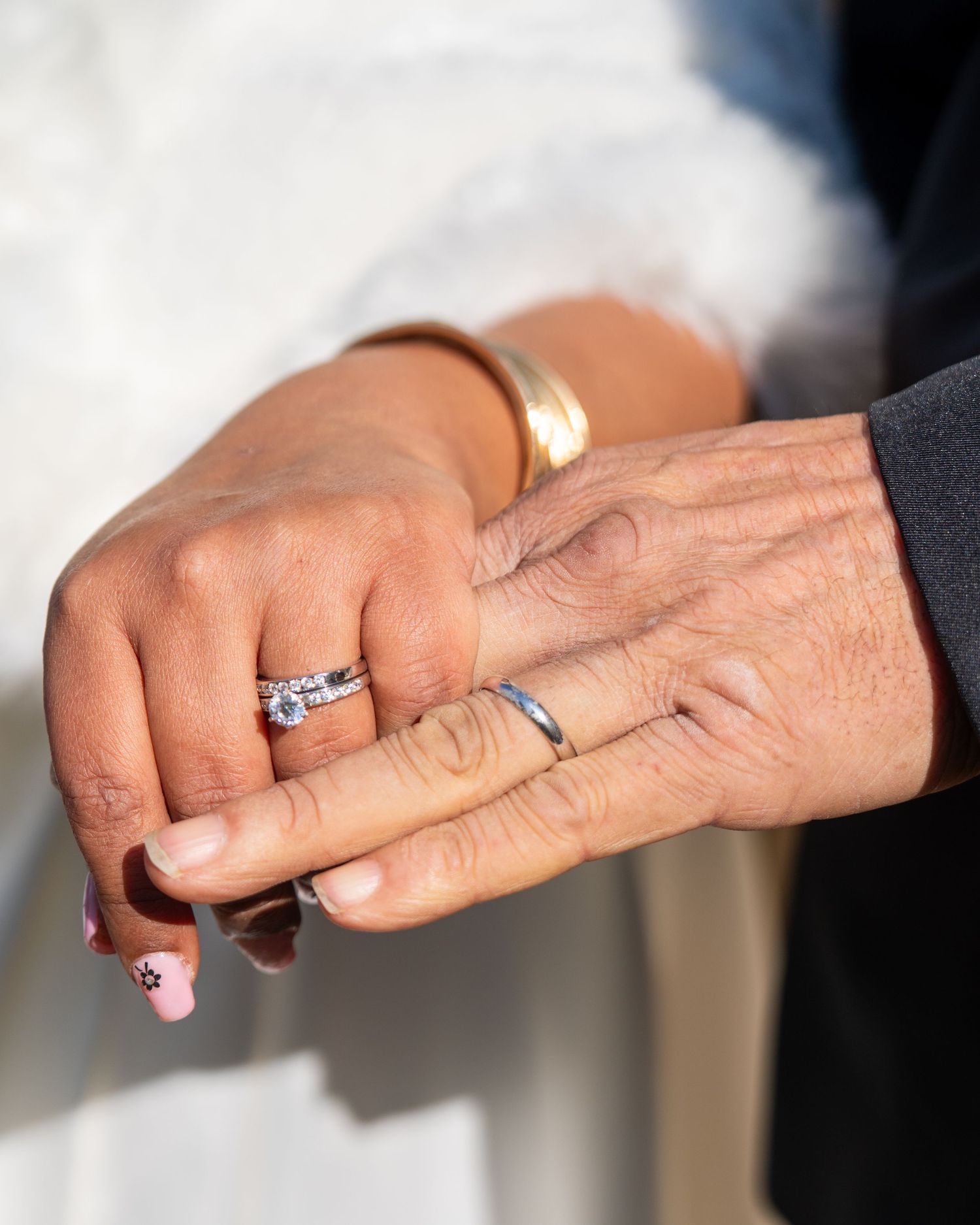 A close-up view of hands wearing elegant wedding rings and engagement rings with sparkling diamonds.