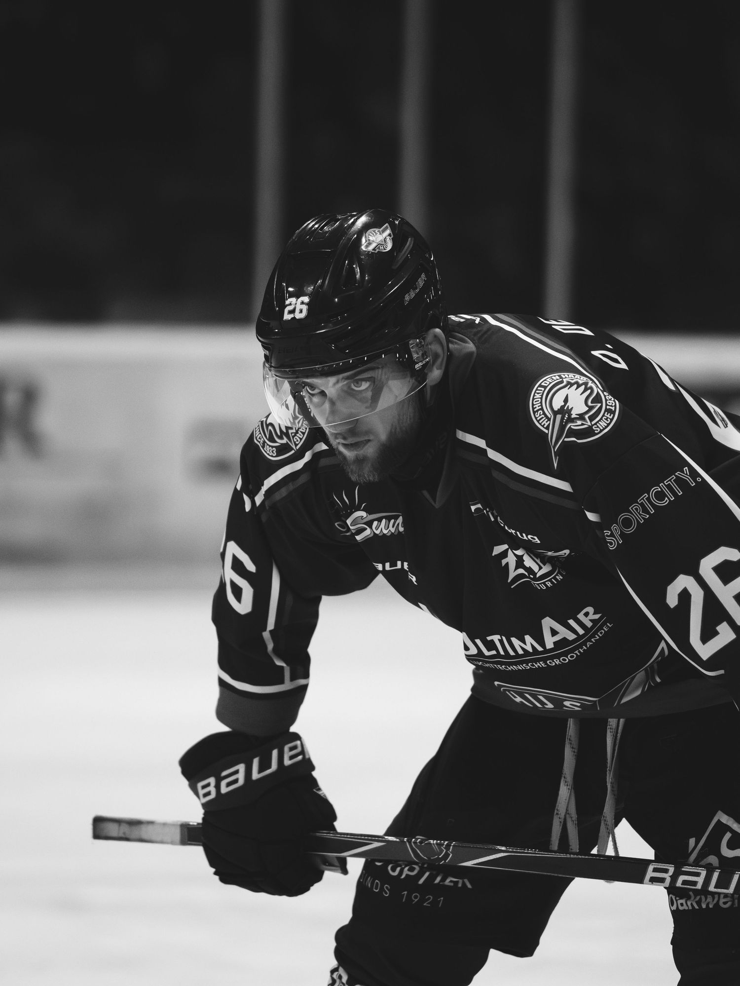 Hockey players in black jerseys lean forward in action poses during an intense game on the ice.