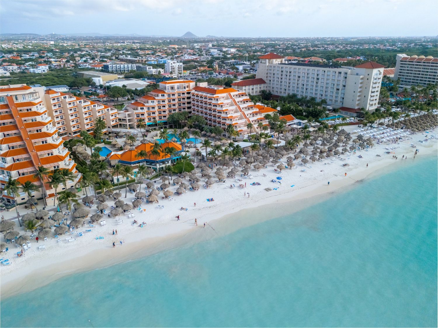 Aerial view of a luxury beachfront resort in Aruba with turquoise Caribbean waters and white sandy beach.