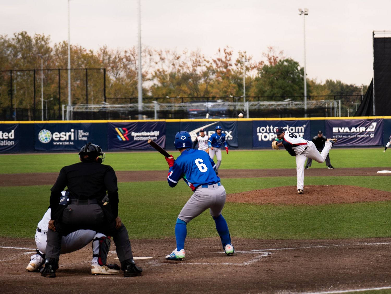 Baseball player slides into home plate during a close play at the plate while the catcher awaits the throw.