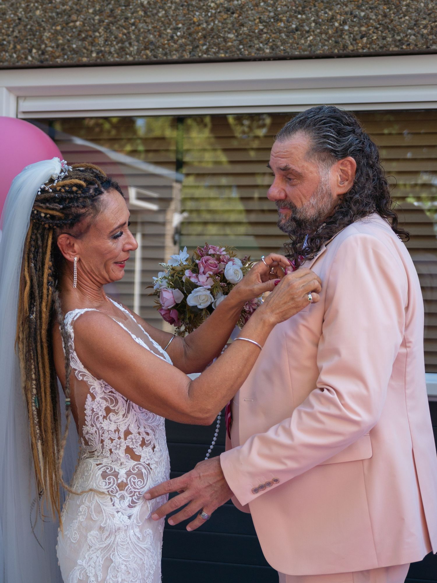 Couple shares intimate moment with bouquet during outdoor wedding celebration.
